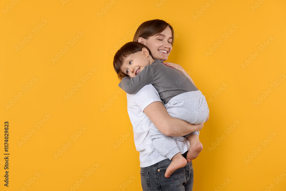 Happy mother with her cute little son on yellow background, space for text Happy mother with her cute little son on yellow background, space for text