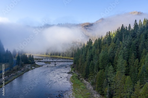 Misty morning over a river and bridge. Thick forest surrounds the tranquil waterway. Selway River, Lowell, Idaho, USA. photo