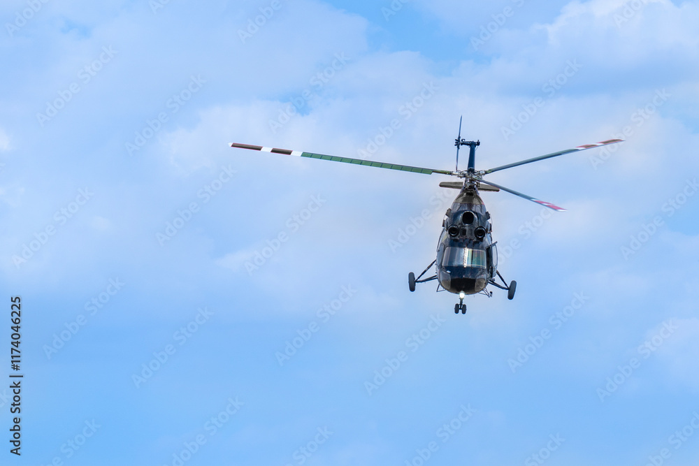 An old Soviet-designed black helicopter flies in the clear sky An old Soviet-designed black helicopter flies in the clear sky