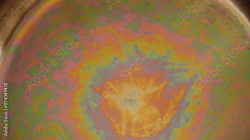 Iridescent color spots on the bottom of a stainless steel pan. Light interference in thin films. Concept of optical effects on familiar objects. Visual physics on kitchen household things