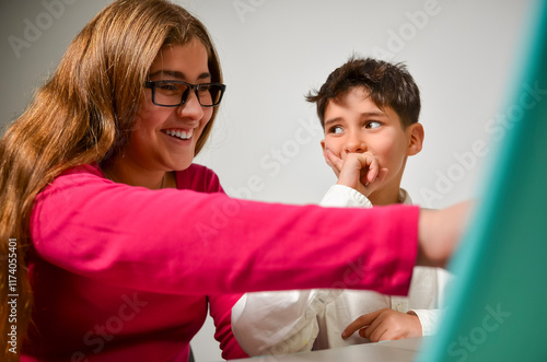 Older sister helping younger brother with homework, showing support and encouragement
