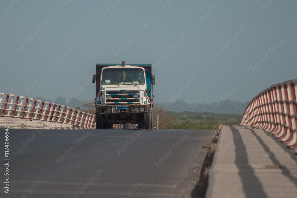 Truck or lorry driving over a bridge in ziguinchor city in southern part od Senegal. Rough road over bridge of casamance river, sunny day, transporting goods.