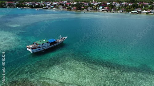 Wooden boat moves slowly in shallow water. Aerial view