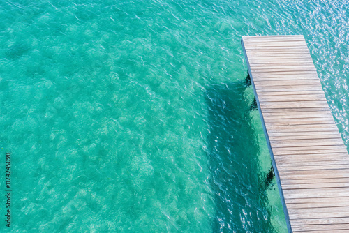 A wooden pier extending over clear turquoise water. photo