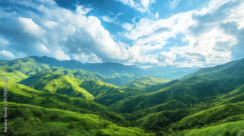 Obraz premium Lush green mountain landscape under a bright blue sky with clouds showcasing tranquility and the beauty of nature