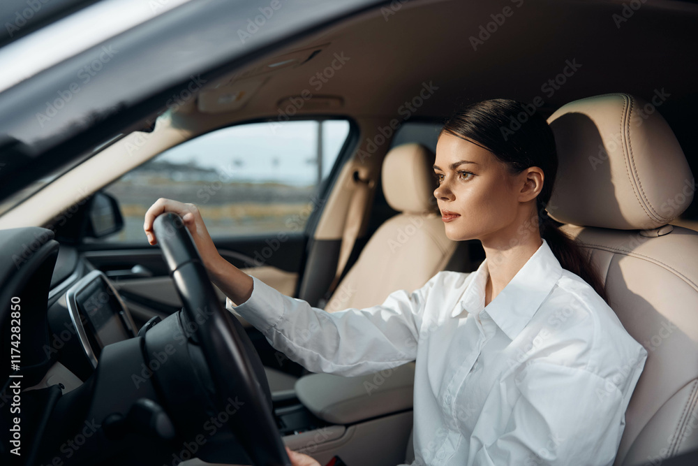 Woman in white shirt, driver's seat, hands on steering wheel, looking at camera