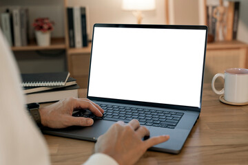 Close-up image of a man working on laptop computer at a table, typing on the laptop keyboard. the laptop with a white screen mockup