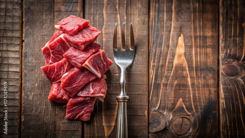 Freshly cut raw beef strips on a fork resting on a wooden table with a rustic background , dailyfood, cuts photo