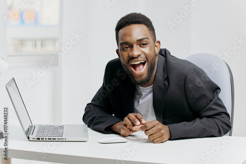 Surprised businessman in formal attire expressing shock while viewing unexpected news on laptop at office desk photo