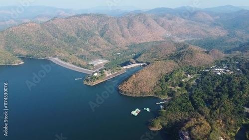 Aerial landscape view of Sri Nakarin Dam is a water storage dam for electricity generation and agriculture in the middle of a valley in Kanchanaburi, Thailand.