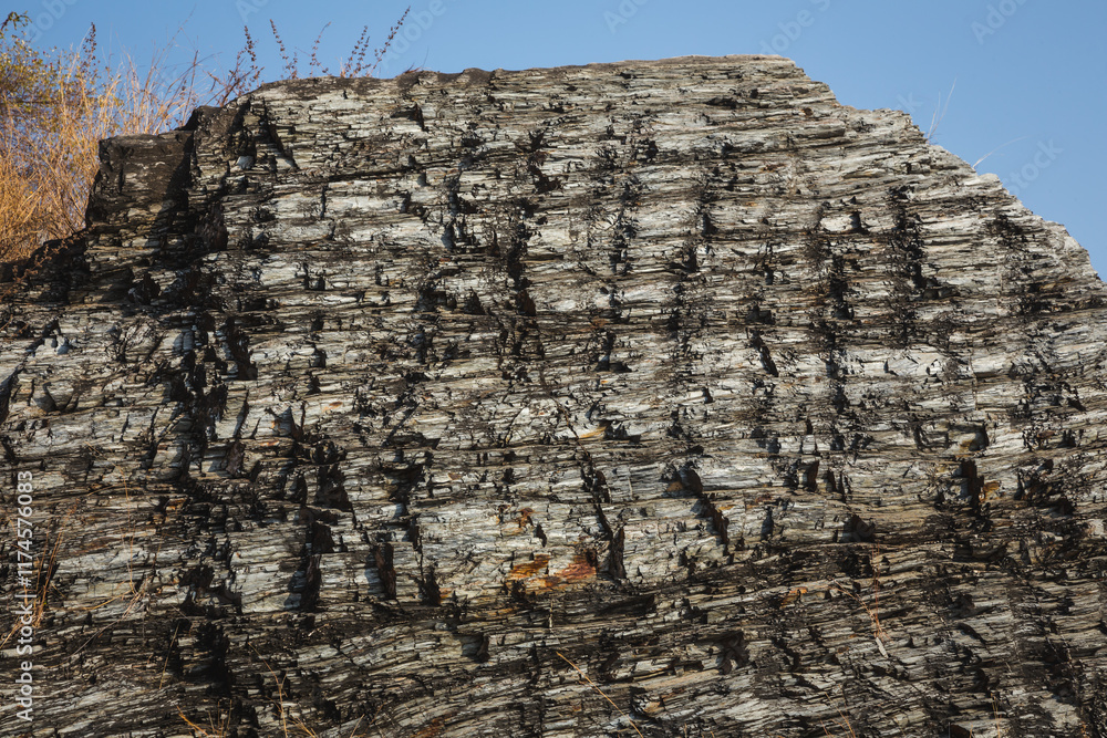A picture of a cliff with light and shadow falling on a rocky surface as a background.