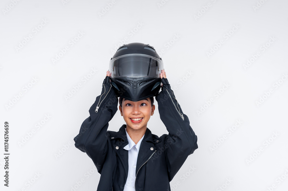 A young rookie Asian woman delivery rider smiles putting on her protective helmet over her head, isolated on a white background. A young rookie Asian woman delivery rider smiles putting on her protective helmet over her head, isolated on a white background.