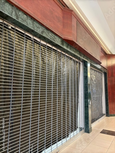 Canvas Print Shuttered storefront with metal security grille at dead shopping mall