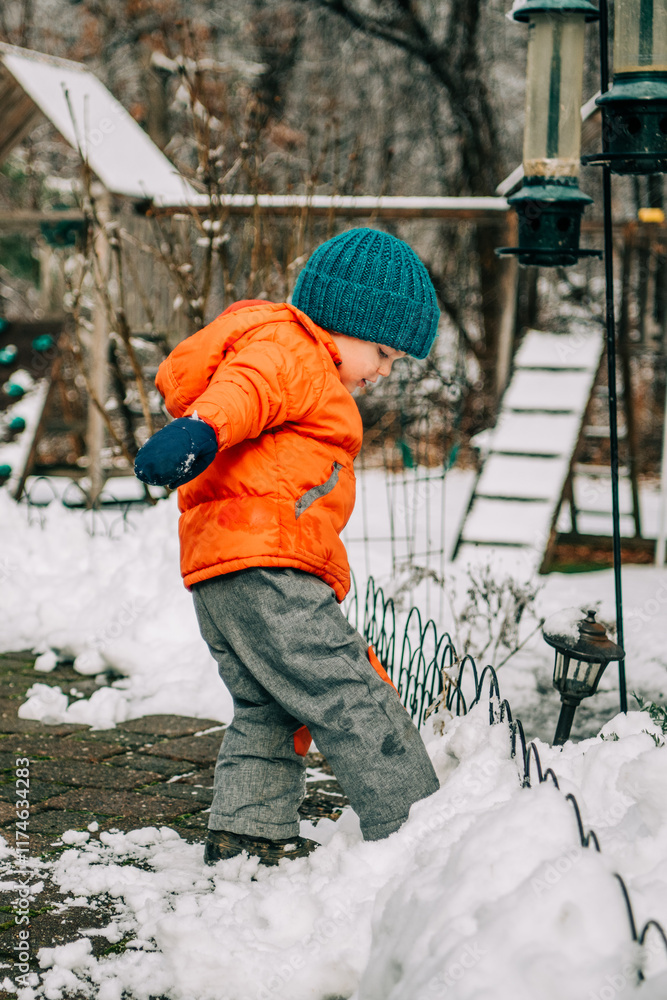 Fototapeta premium Child stepping into snow by fence