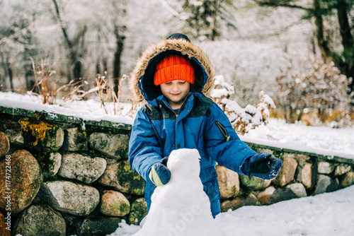 Smiling child shaping snowman outdoors photo