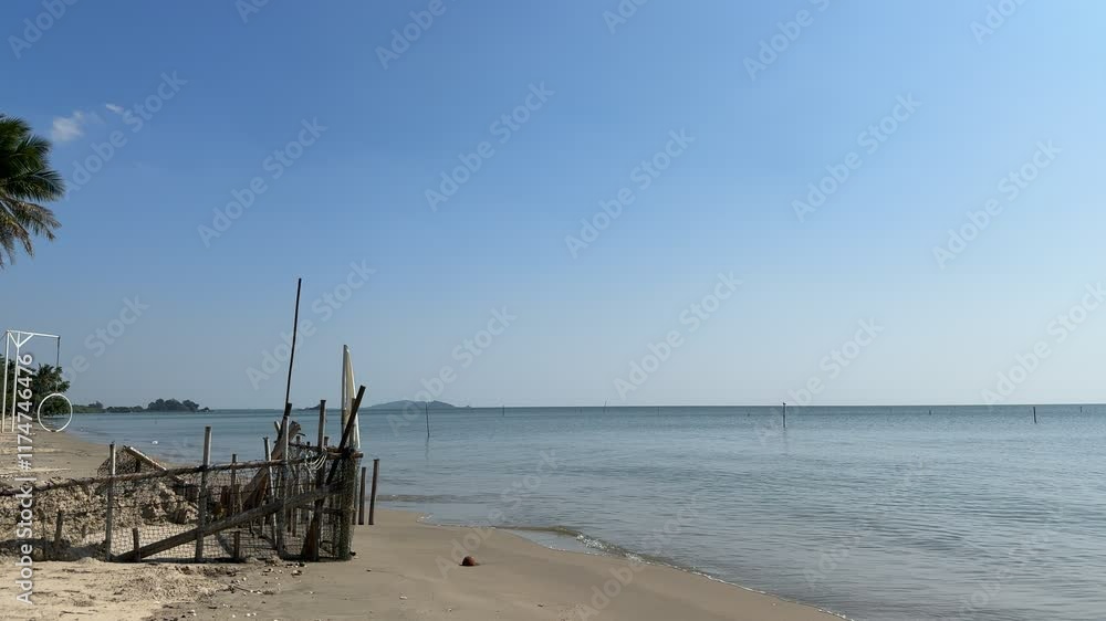 Tranquil Beachscape: Serene coastal view of a calm sea under a clear blue sky, with a rustic wooden structure on the sandy shore, palm trees in the background. Evokes peace and tranquility. Tranquil Beachscape: Serene coastal view of a calm sea under a clear blue sky, with a rustic wooden structure on the sandy shore, palm trees in the background. Evokes peace and tranquility.