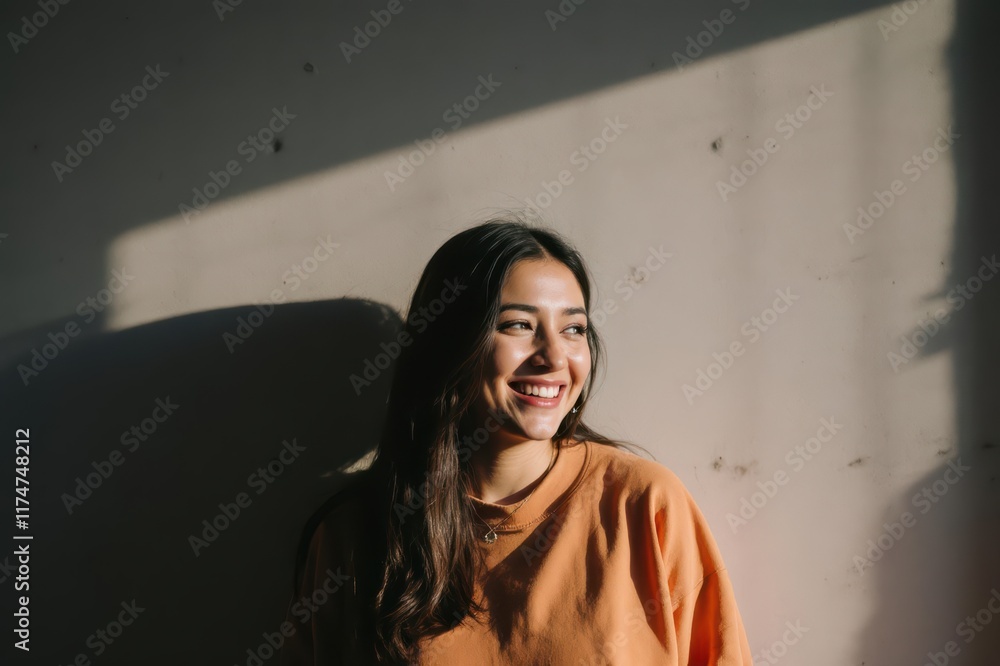 Fototapeta premium Smiling woman under shadow in front of concrete wall