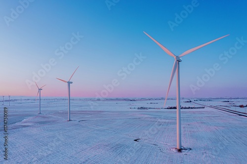 Snowy landscape with wind turbines at dawn. Sustainable energy production in a rural setting. Sunrise hues over the winter fields. , Fort Macleod, Alberta, USA photo