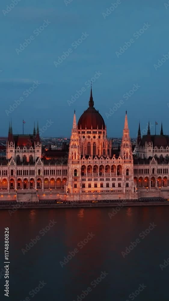 Cinematic shot of Orszaghaz at night. Breathtaking illuminated building of Hungarian parliament on Danube river waterfront. Budapest, Hungary