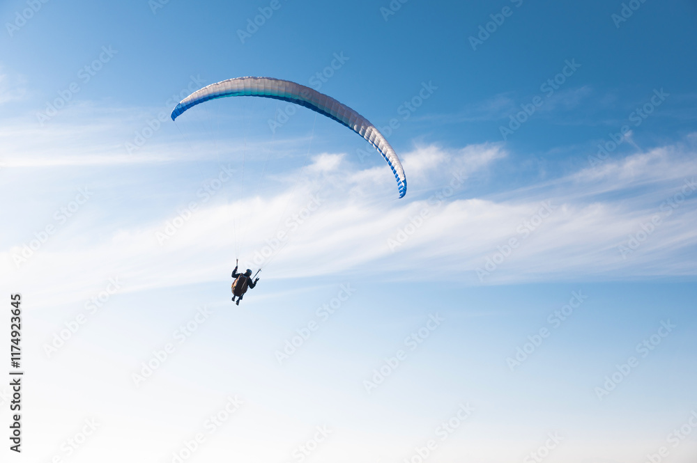 Paragliding sport, man alone flies in blue sky with clouds, freedom and loneliness. Hobby for adults Paragliding sport, man alone flies in blue sky with clouds, freedom and loneliness. Hobby for adults
