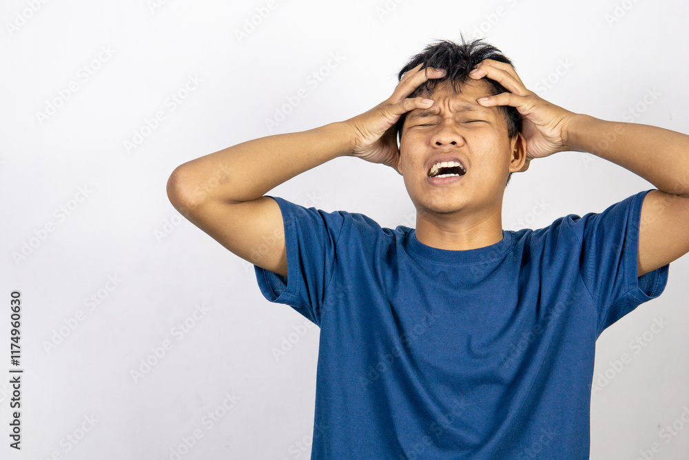 Stressed and frustrated Asian young man wearing blue t-shirt looking depressed isolated on white background Stressed and frustrated Asian young man wearing blue t-shirt looking depressed isolated on white background