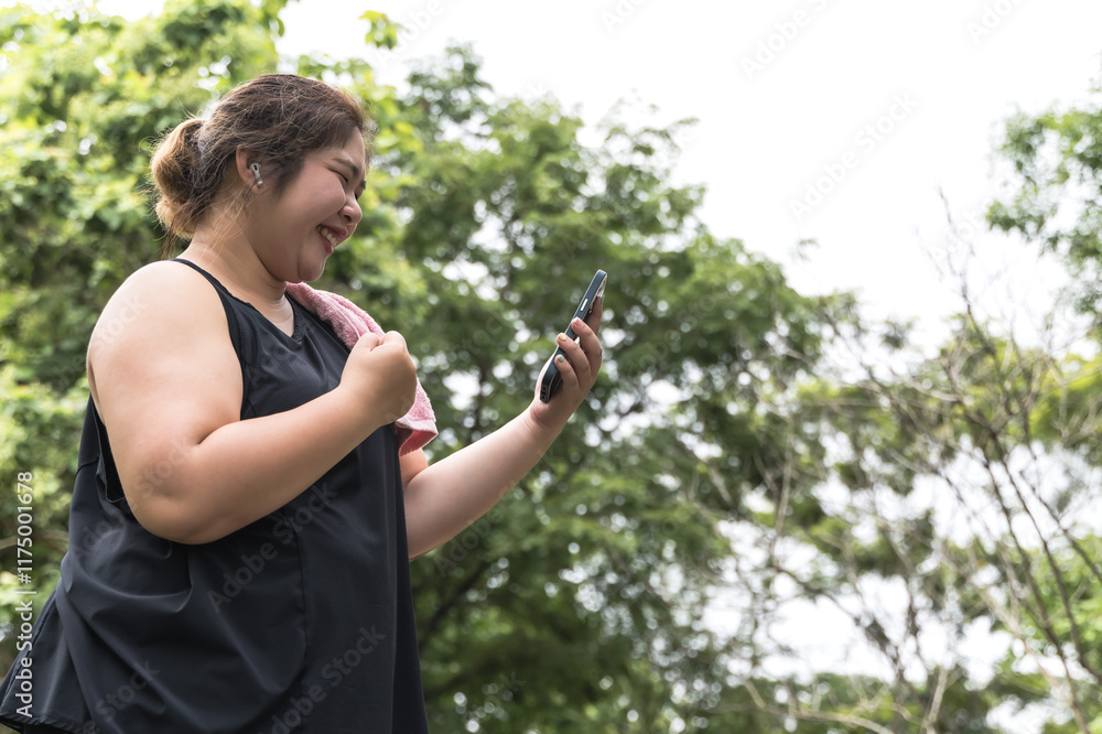 Asian fat fitness woman looking at smartphone during work out in public park Asian fat fitness woman looking at smartphone during work out in public park