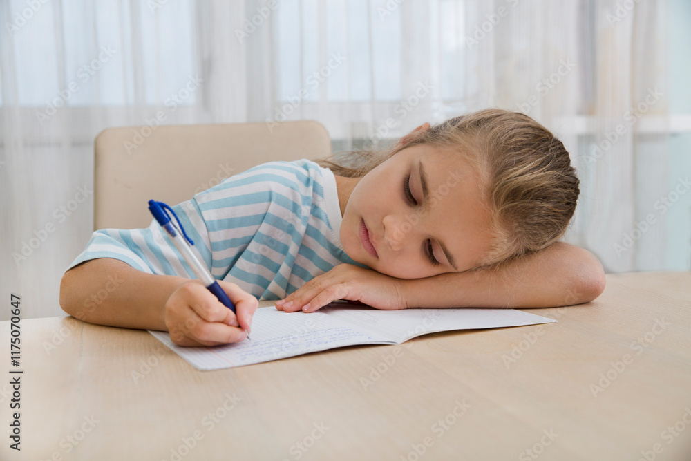 sad tired girl of eight writes in notebooks, does homework sitting at the table at home sad tired girl of eight writes in notebooks, does homework sitting at the table at home