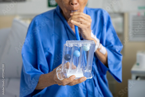 фотографія Senior asian man using incentive spirometer device for breathing exercise rehabi