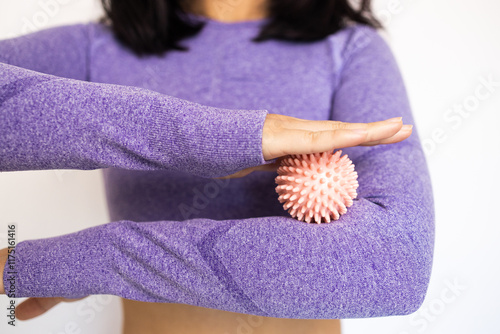 Cropped view of young woman in sportswear holding manual massage ball and standing on white background, balancing energy and holistic healing concept. photo