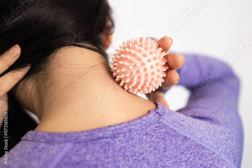 Young brunette woman in sportswear massaging neck with manual massage ball, balancing energy and holistic healing concept, myofascial release photo