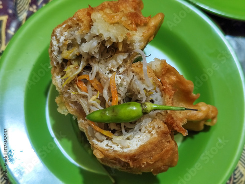 Tahu Isi or Tahu Brontak is an Indonesian food made from fried tofu with several types of vegetables including cabbage, mustard greens, bean sprouts and carrots. Served with chili on a green plate. photo