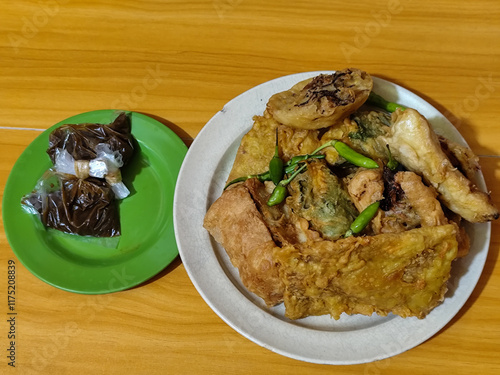 Gorengan, a traditional Indonesian street food consisting of tahu brontak, fried banana, bakwan, tempe mendoan, etc. Served with green chili and petis. photo