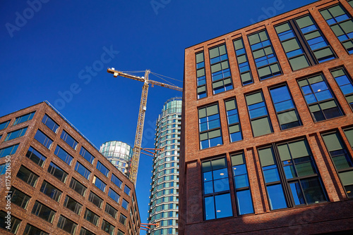 Photography Modern brick buildings and construction crane against vibrant blue sky