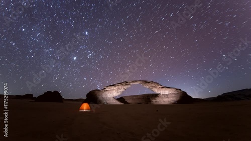 Time lapse of stars motion in rainbow arch night camping tent, with beautiful rock Al ula, Madinah,  Saudi Arabia
