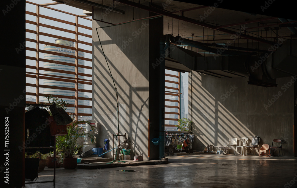 Morning sunlight shines through Wooden Battens to The washing area for maid and Variety of Chairs near concrete wall on parking lot of Condominium building. use it as your Wallpaper, Poster and Space.