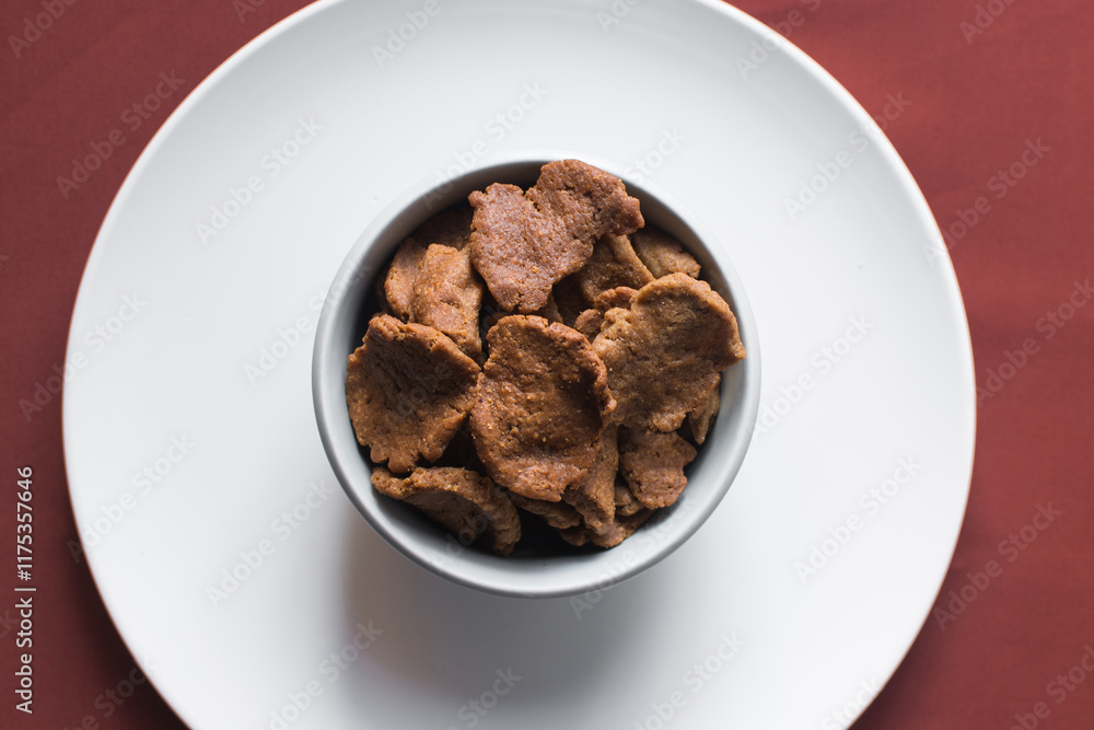 Overhead view of kuli-kuli in a white bowl, top view of nigerian groundnut cakes in a bowl, fresh homemade nigerian kulikuli in a ceramic bowl Overhead view of kuli-kuli in a white bowl, top view of nigerian groundnut cakes in a bowl, fresh homemade nigerian kulikuli in a ceramic bowl