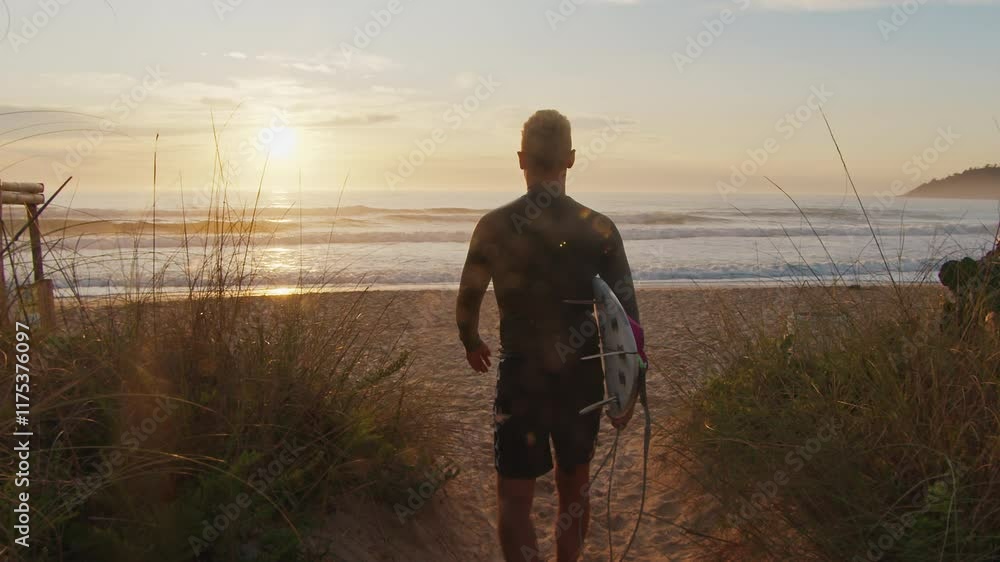 Man surfer goes forward the ocean with surfing board at sunrise Man surfer goes forward the ocean with surfing board at sunrise