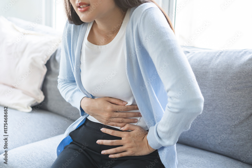 Fototapeta premium Sick asian young woman in pain, hand holding belly, stomach pain from food poisoning, girl hurt abdomen ache and digestive problem, gastritis or diarrhea. Health care inflammation, abdominal problem