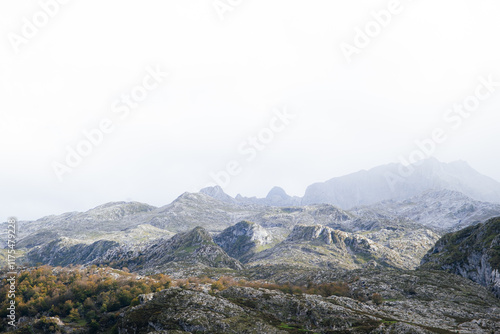 A view of the Picos de Europa National Park in Asturias, Spain. This photo was taken from the Lagos de Covadonga, by Lago de la Ercina. The sunlight is hitting the mountains as the clouds pass over. photo