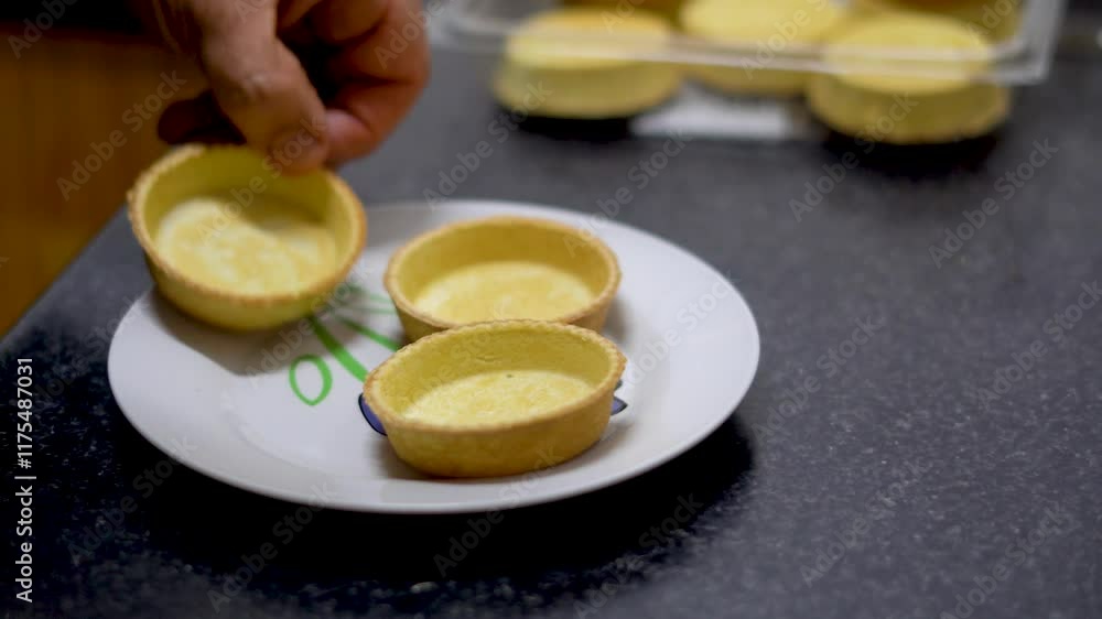 A person places some tartlets on a plate, ready to be filled. Real time. A person places some tartlets on a plate, ready to be filled. Real time.