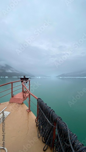 Proa de barco navegando no mar com icebergs e geleira ao fundo. Patagônia Chilena photo