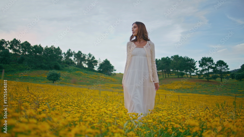 Relaxed model strolling flowers field. Lady white dress looking camera walking Relaxed model strolling flowers field. Lady white dress looking camera walking