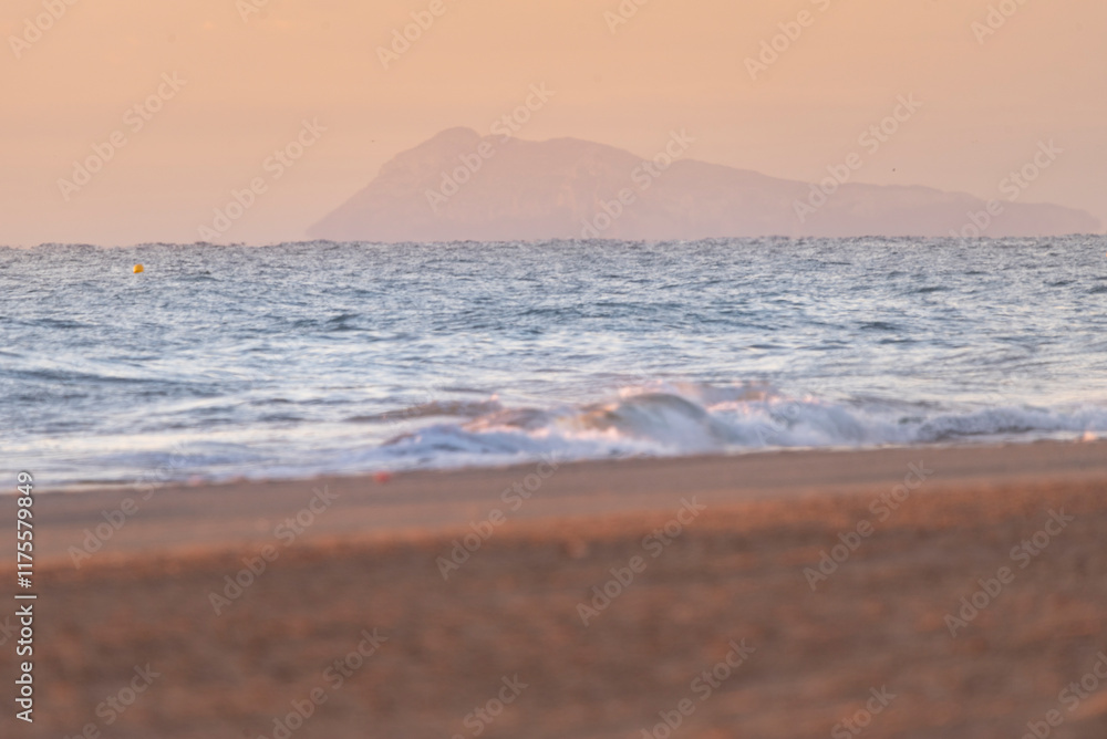 Fototapeta premium Waves on the beach. Sunrise on the beach. A nice sunrise. Lights and reflections of sunrise on a beautiful beach - Mediterranean Sea coastal tsunami warning
