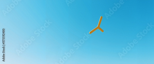 Yellow boomerang flying in clear blue sky