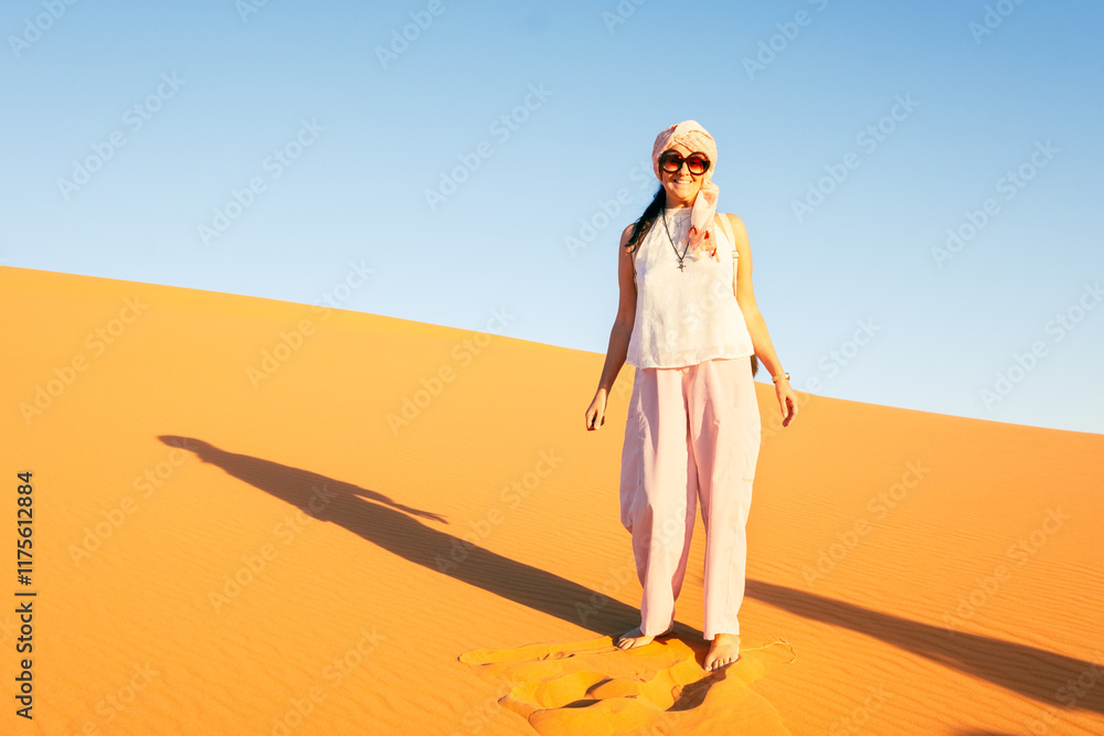 A beautiful middle-aged woman smiles happily posing on a beautiful sand dune in the Sahara desert. It is a sunny day and the sun is warm and bright. Travel, adventure and happiness concept A beautiful middle-aged woman smiles happily posing on a beautiful sand dune in the Sahara desert. It is a sunny day and the sun is warm and bright. Travel, adventure and happiness concept