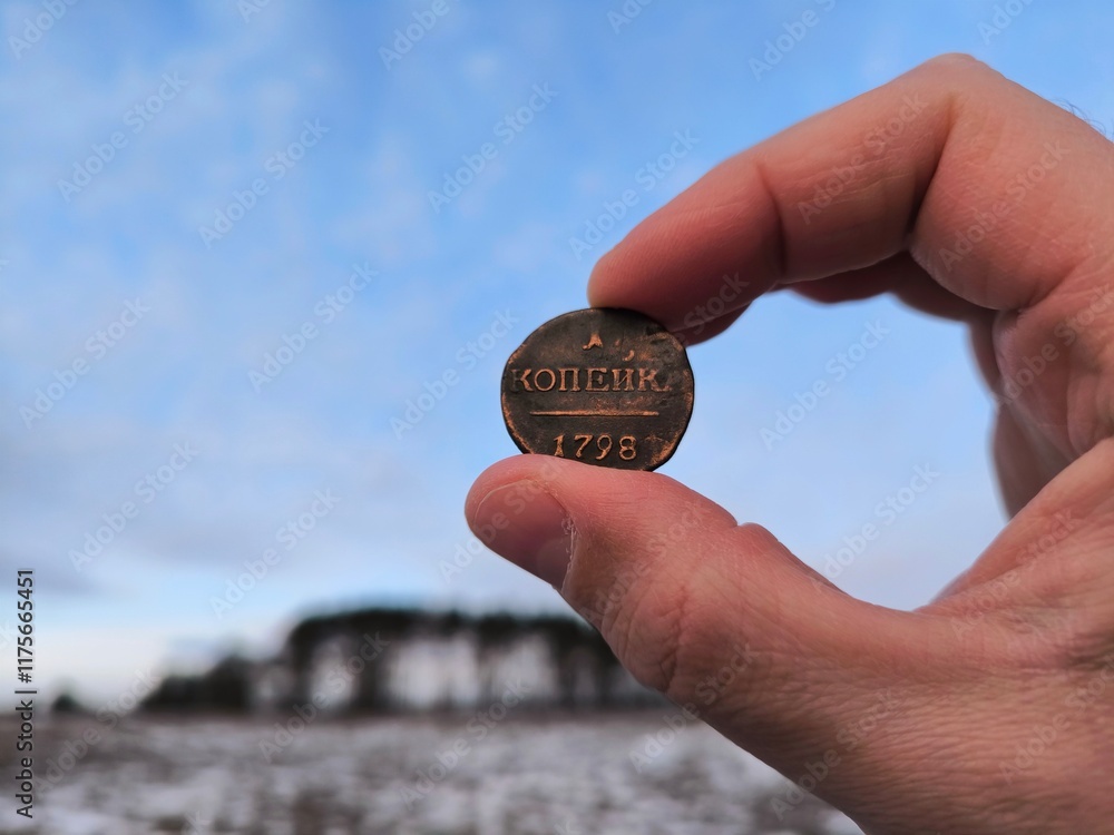 An old copper coin, a hand holding an ancient copper coin in a field. An ancient coin in your hands. Antique copper coin An old copper coin, a hand holding an ancient copper coin in a field. An ancient coin in your hands. Antique copper coin