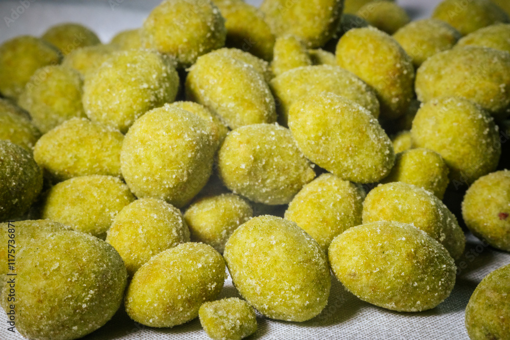 A close-up view of bright yellow-green wasabi-flavored nuts coated in a fine powder, creating a spicy and crunchy snack. Blurred background for emphasis. A close-up view of bright yellow-green wasabi-flavored nuts coated in a fine powder, creating a spicy and crunchy snack. Blurred background for emphasis.