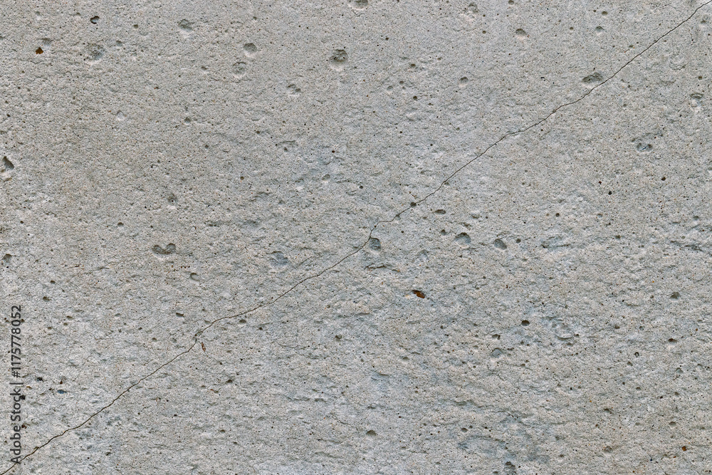 Fototapeta premium a gray concrete wall cracked diagonally. texture background, close-up