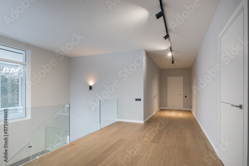 A spacious corridor on the second floor of a country house. Finishing, beige laminate, .stairs with glass railings. photo