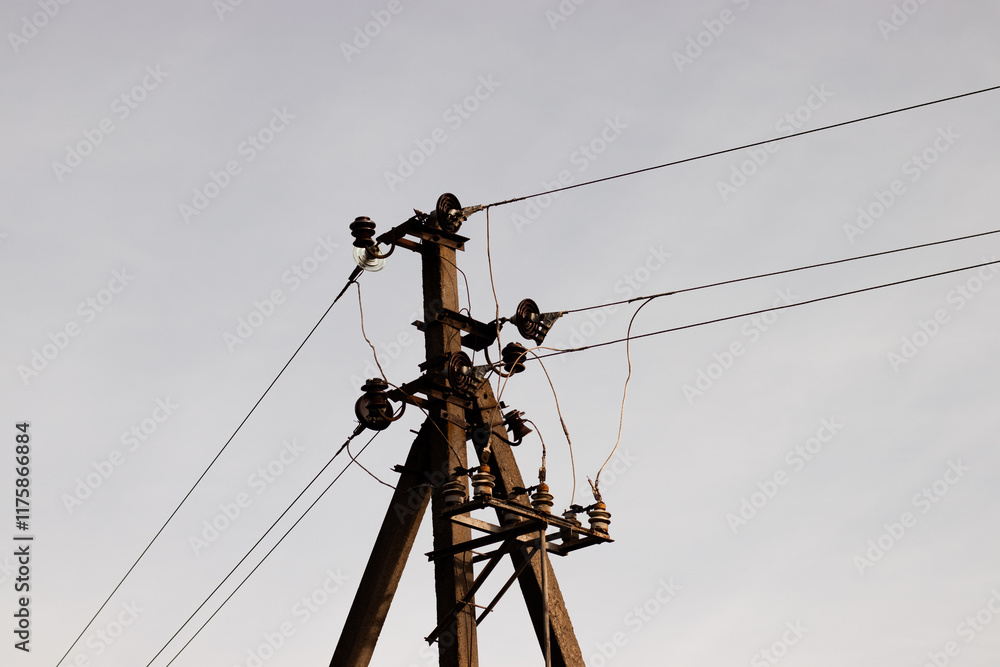 Close-up of the top part of an electric pole with power lines stretching across the sky. A clear view of the cables and pole structure, showcasing industrial energy infrastructure against a blue sky Close-up of the top part of an electric pole with power lines stretching across the sky. A clear view of the cables and pole structure, showcasing industrial energy infrastructure against a blue sky